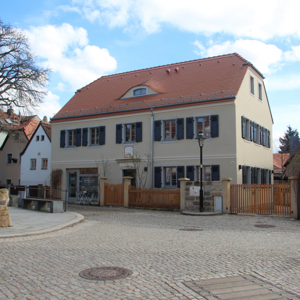 ein Haus mit rotem Ziegeldach an einem gepflasterten Platz